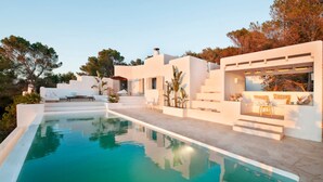 Un espace moderne aménagé au bord de la piscine, avec une eau cristalline, une architecture blanche et des marches menant à un espace de détente abrité.