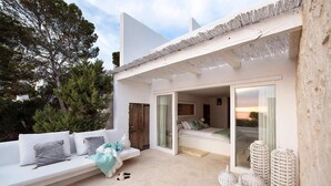 Une chambre à coucher moderne et minimaliste, dotée d’une grande porte-fenêtre coulissante qui donne sur un balcon.