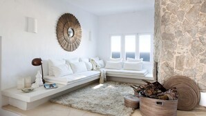 Un salon moderne avec un canapé blanc, un grand miroir et un mur en pierre.