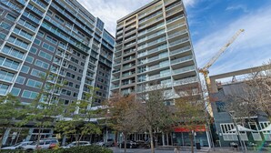 A high-rise building with multiple floors, large windows, and a construction crane in the background. - Swainson on Hindmarsh (Adelaide)