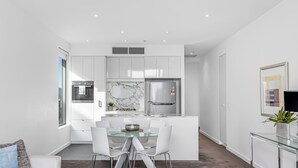 A modern kitchen with white cabinetry, a marble backsplash, and stainless steel appliances. - Swainson on Hindmarsh (Adelaide)