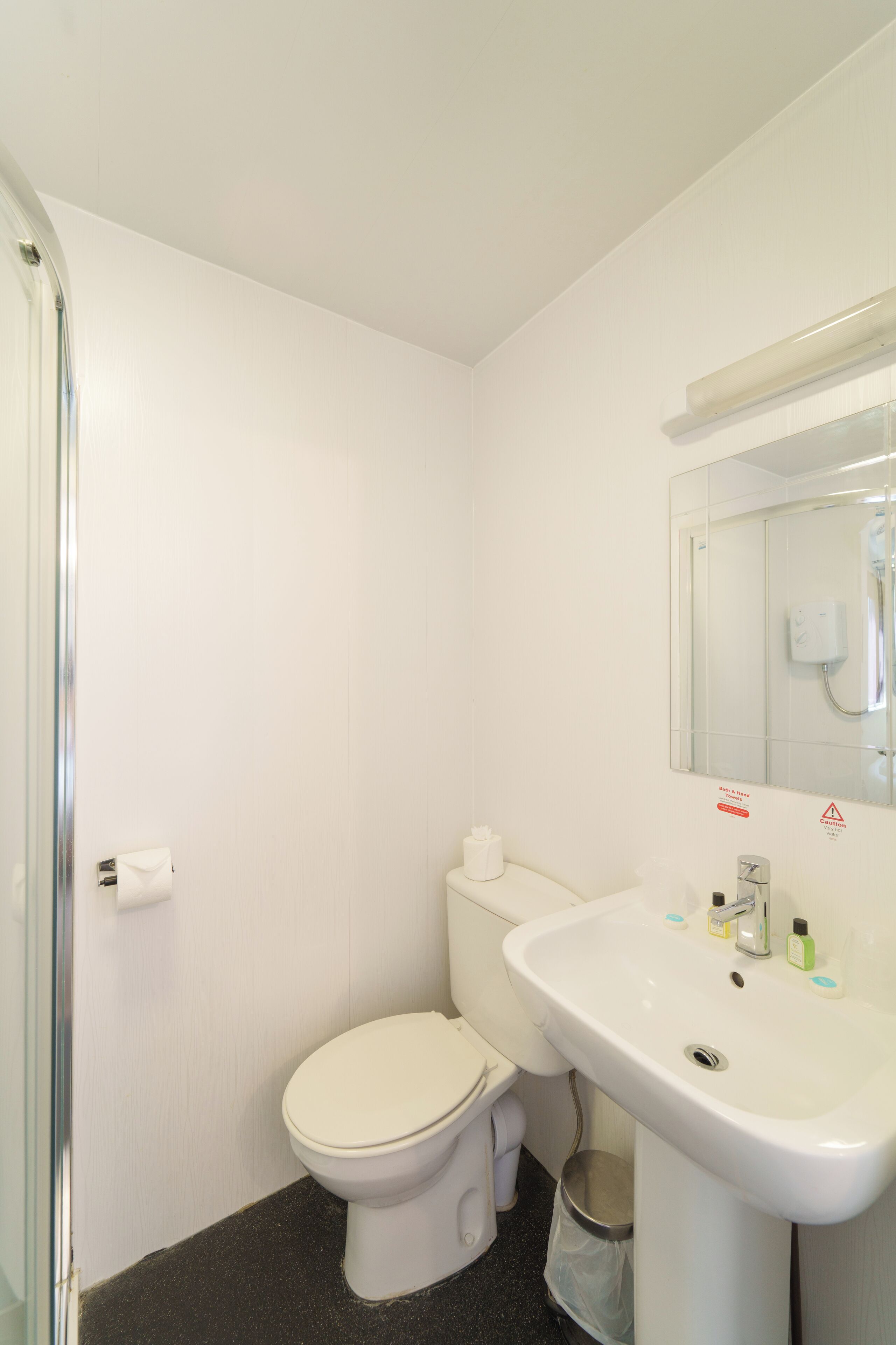 Een kleine, schone badkamer met toilet, wastafel en spiegel.