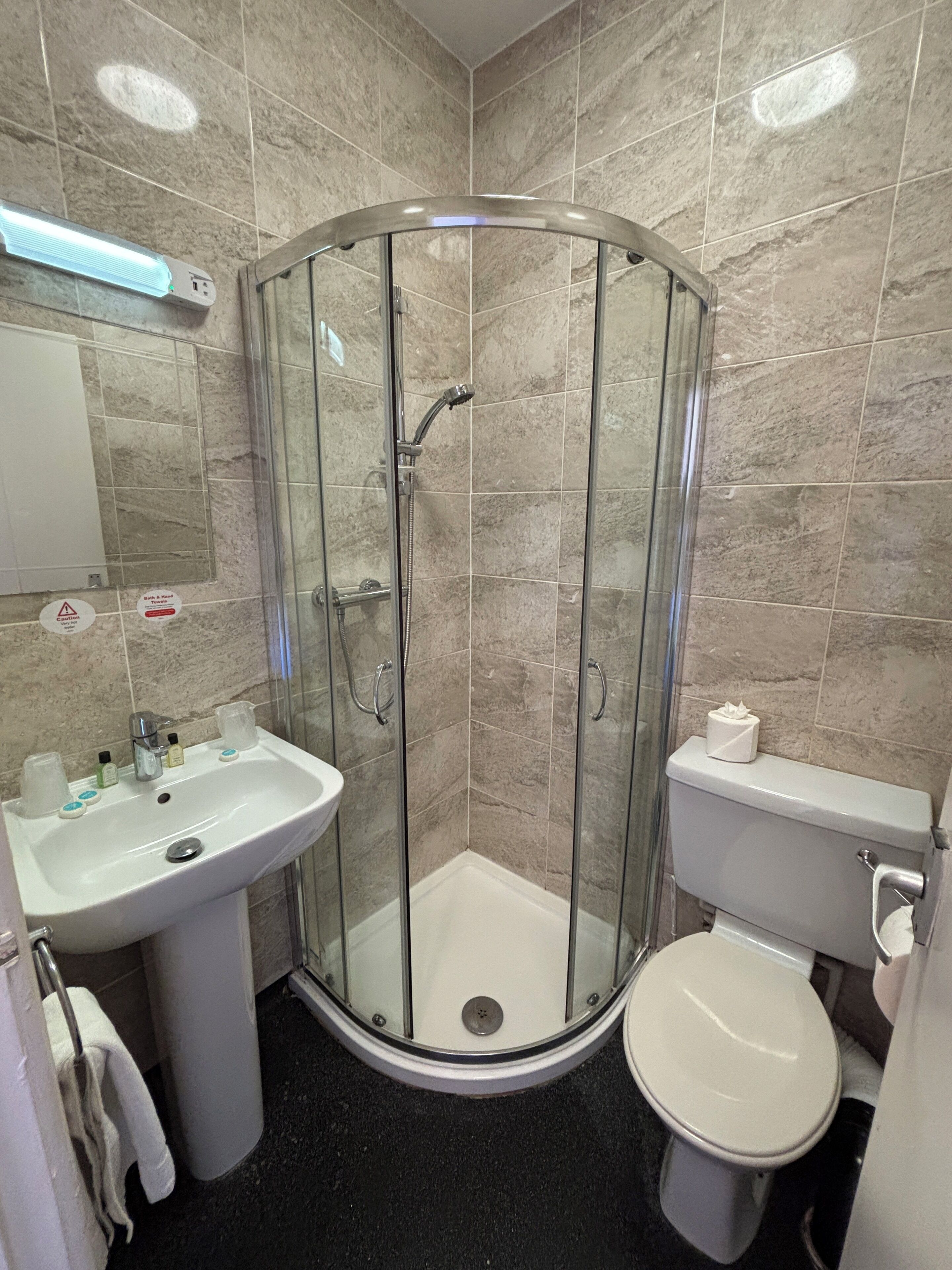 A bathroom with a glass-enclosed shower, a sink, and a toilet.