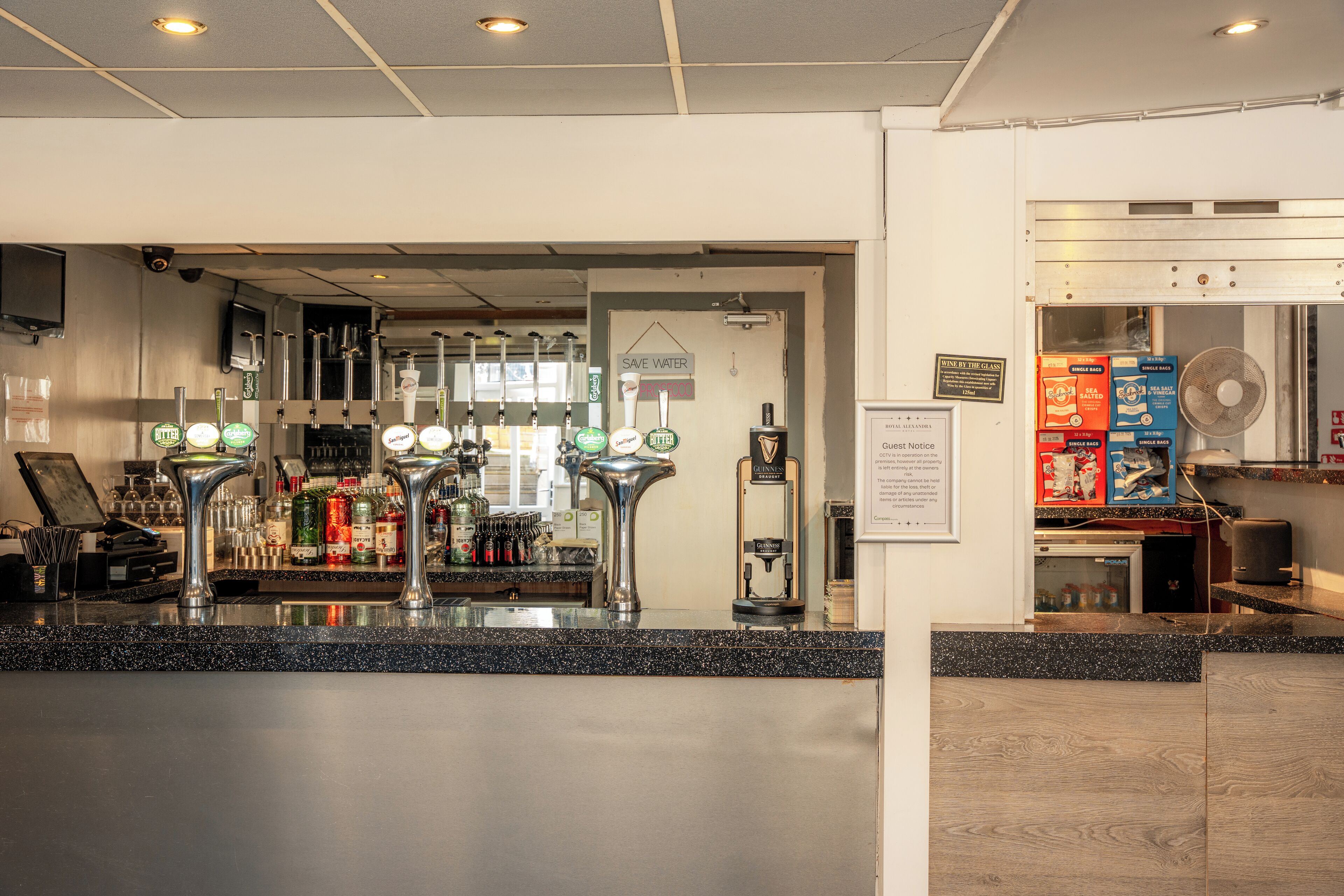 A bar area with multiple taps, a fan, and a refrigerator.