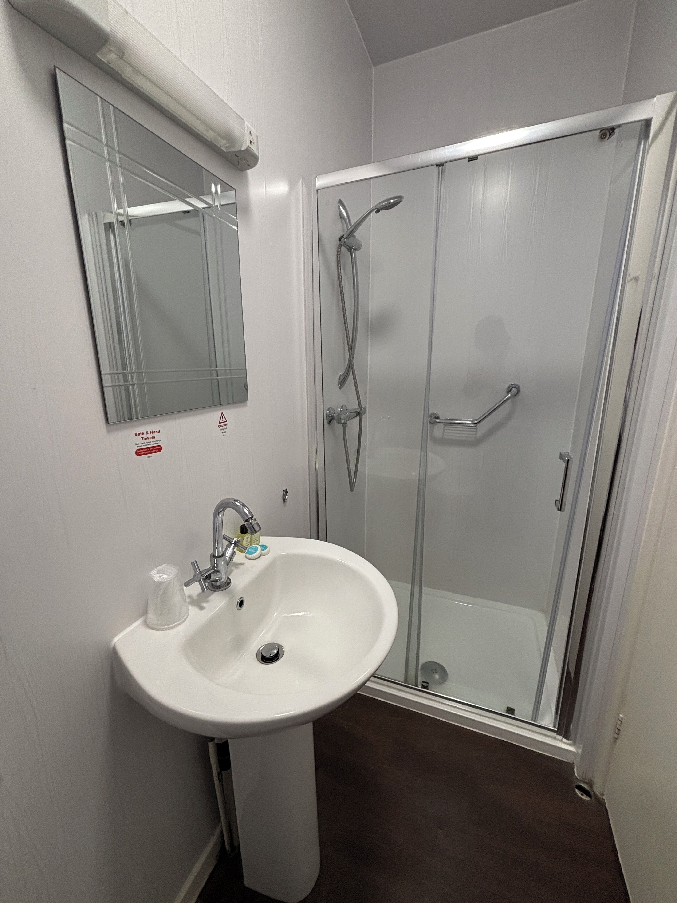A bathroom with a white sink, a mirror, and a glass-enclosed shower.
