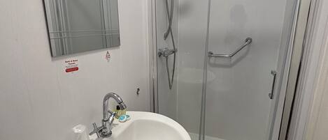 A bathroom with a white sink, a mirror, and a glass-enclosed shower.