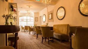 A lobby with a grand chandelier, a piano, and a seating area with chairs and sofas. - The Royal Alexandra Hotel by Compass Hospitality (Blackpool)