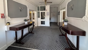 A hallway with patterned carpet, a ceiling fan, and decorative wall mirrors. - The Royal Alexandra Hotel by Compass Hospitality (Blackpool)