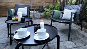 An outdoor seating area with two round tables, each with a white cup and saucer, and a candle on one table. - B&B Arena Prestige Rooms (Pula)