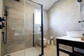 A modern bathroom with a glass-enclosed shower, a toilet, and a sink with a white basin.