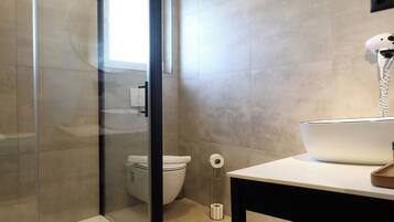 A modern bathroom with a glass shower enclosure, a toilet, and a sink with a mirror.