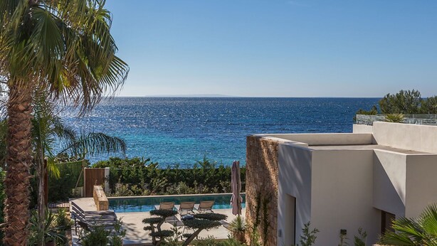 Zona de piscina amb gandules i vista al mar.