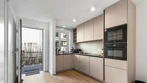 A modern kitchen with a built-in oven, a coffee maker, and a sink. - Luxury duplex apartment with terrace (Sylt)