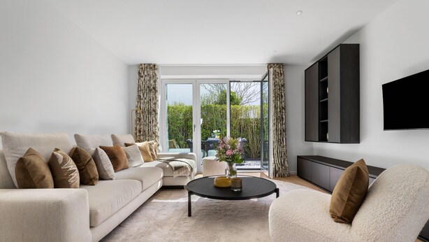 A modern living room with a sofa, armchairs, a coffee table, and a TV mounted on the wall. - Luxury duplex apartment with terrace (Sylt)
