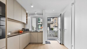 A modern kitchen with a built-in oven, a toaster, and a sink. There is a small window with a view of the outside. - Luxury duplex apartment with terrace (Sylt)
