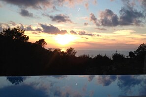 A sunset over a body of water with trees silhouetted against the sky. - My Rental Homes - Villa Sun with sea view, pool and large garden (Sant Antoni De Portmany)