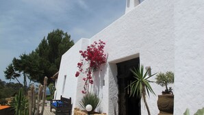 A white building with a wooden door and a bench outside. - My Rental Homes - Villa Sun with sea view, pool and large garden (Sant Antoni De Portmany)