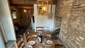 A wooden dining table set for six with a stone wall and wooden ceiling. - Gîte "la Cazelle (Saint-Chels)