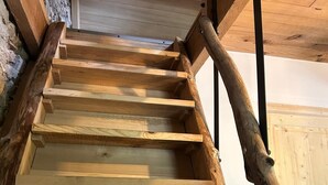 A wooden staircase with a rustic design, featuring a handrail and a stone wall on one side. - Gîte "la Cazelle (Saint-Chels)