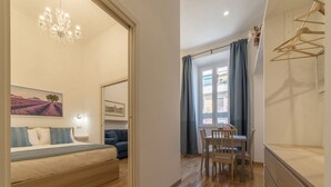A bedroom with a bed, a dresser, a desk, and a chair. There is a window with curtains, a chandelier, and a painting on the wall. - CS Termini Nazionale Apt n. 4 (Roma)