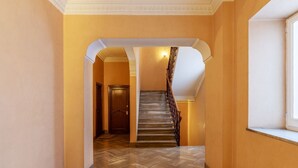 Un couloir avec un plancher en bois, un escalier muni d’une rampe et une porte au bout.