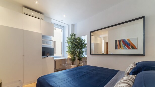 Une chambre moderne avec un grand lit, un bureau et une plante en pot.