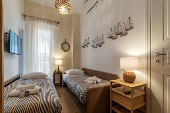 A hotel room with two beds, a sofa, a small table, and decorative wall art.