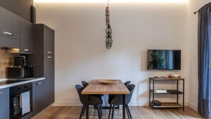 A modern kitchen with dark cabinetry, a wooden dining table, and a hanging light fixture. - CS Vatican Metro Apartment (Roma)