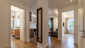 A spacious hallway with wooden flooring, white walls, and a large mirror. - CS Vatican Metro Apartment (Roma)
