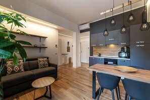 A modern kitchen with dark cabinets, a wooden countertop, and pendant lighting.