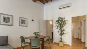Een eetgedeelte met een houten tafel, vier stoelen, een bank en kunstwerken in lijsten aan de wanden.