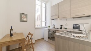 A compact kitchen with a dining area, a microwave, a sink, and a window providing natural light.
