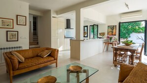 Ein modernes Wohnzimmer mit einer Ledersofa, einem Glastisch und einem Essbereich mit Holzmöbeln.