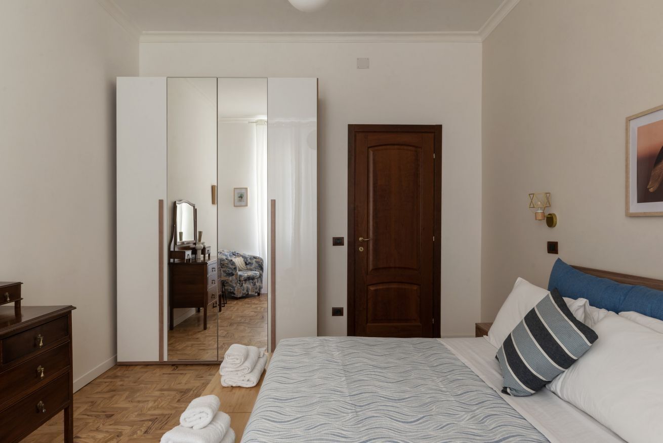 A bedroom with a bed, a wardrobe, a door, and a mirror.