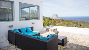 A modern outdoor seating area with wicker furniture and a view of the ocean and a mountain. - My Rental Homes - Villa Rigel with private pool and terraces (San Jose)
