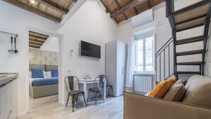 Een moderne, open woonkamer met keuken, eethoek en een bank.