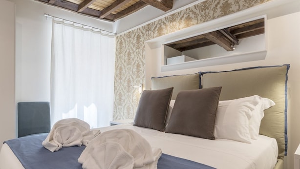A neatly made bed with a blue and white bedspread, two pillows, and two folded towels.