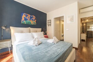 A hotel room with a large bed, a nightstand, a lamp, and a painting on the wall. - Industrial Chic Loft Apartment in Historical Building (Roma)