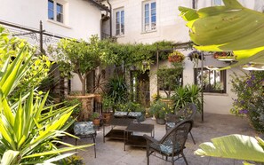 An outdoor patio with a table and chairs, surrounded by potted plants and a variety of flowers. - Exclusive B&B Suites, Apartments, Spa & Fitness<br>The Augustinian House an (AVIGNON)
