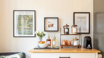 A kitchen counter with a coffee machine, a framed Monet painting, and a framed coffee machine instruction manual.