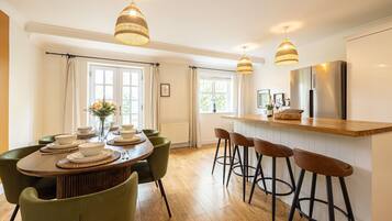 A modern kitchen with a wooden island, bar stools, and pendant lighting.
