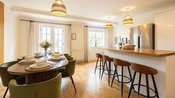 A modern kitchen with a wooden island, bar stools, and pendant lighting.