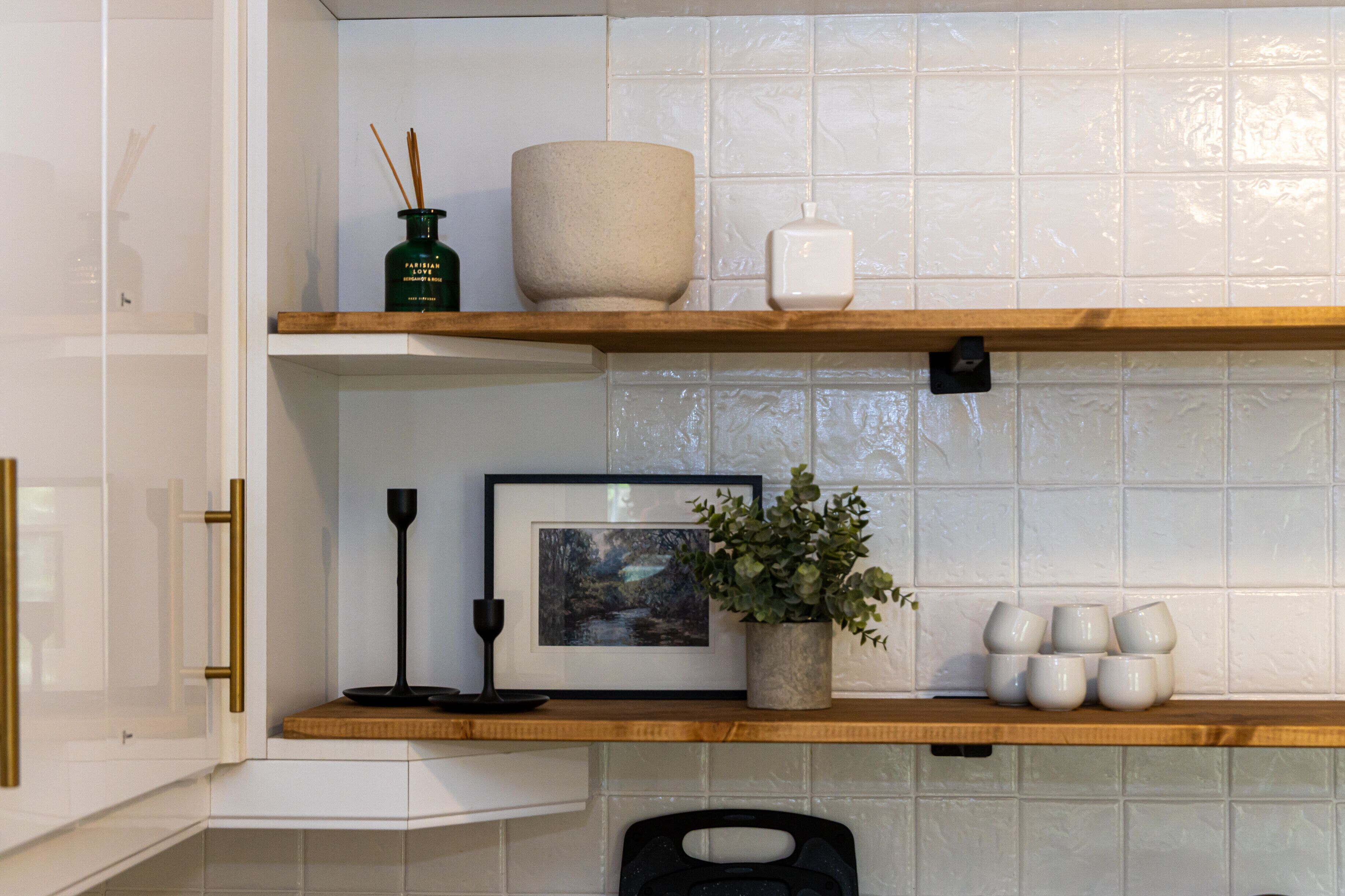 A kitchen with white cabinets, a wooden countertop, and a tiled backsplash.