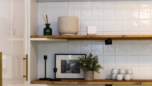 A kitchen with white cabinets, a wooden countertop, and a tiled backsplash.