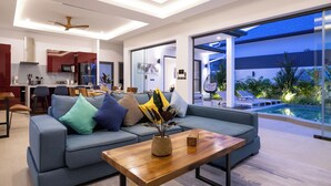 A modern living room with a sofa, a coffee table, and a dining area with chairs and a table. - Villa Malaki, pool villa 2 bedrooms at rawai (Tambon Rawai)