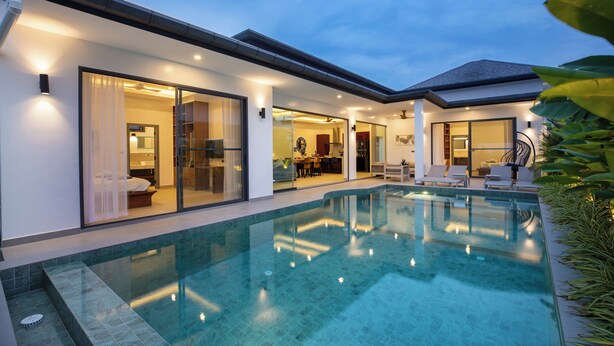 A modern house with a swimming pool, glass doors leading to a dining area, and a well-lit interior. - Villa Malaki, pool villa 2 bedrooms at rawai (Tambon Rawai)