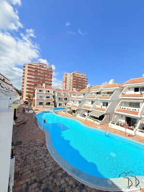 Um resort com uma grande piscina cercada por edifícios brancos com telhados vermelhos.