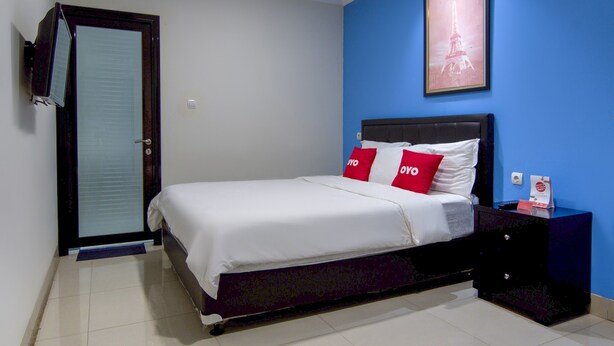 Een slaapkamer met een bed, een nachtkastje, een lijst met een foto van de Eiffeltoren, en een deur met een handdoek erover.