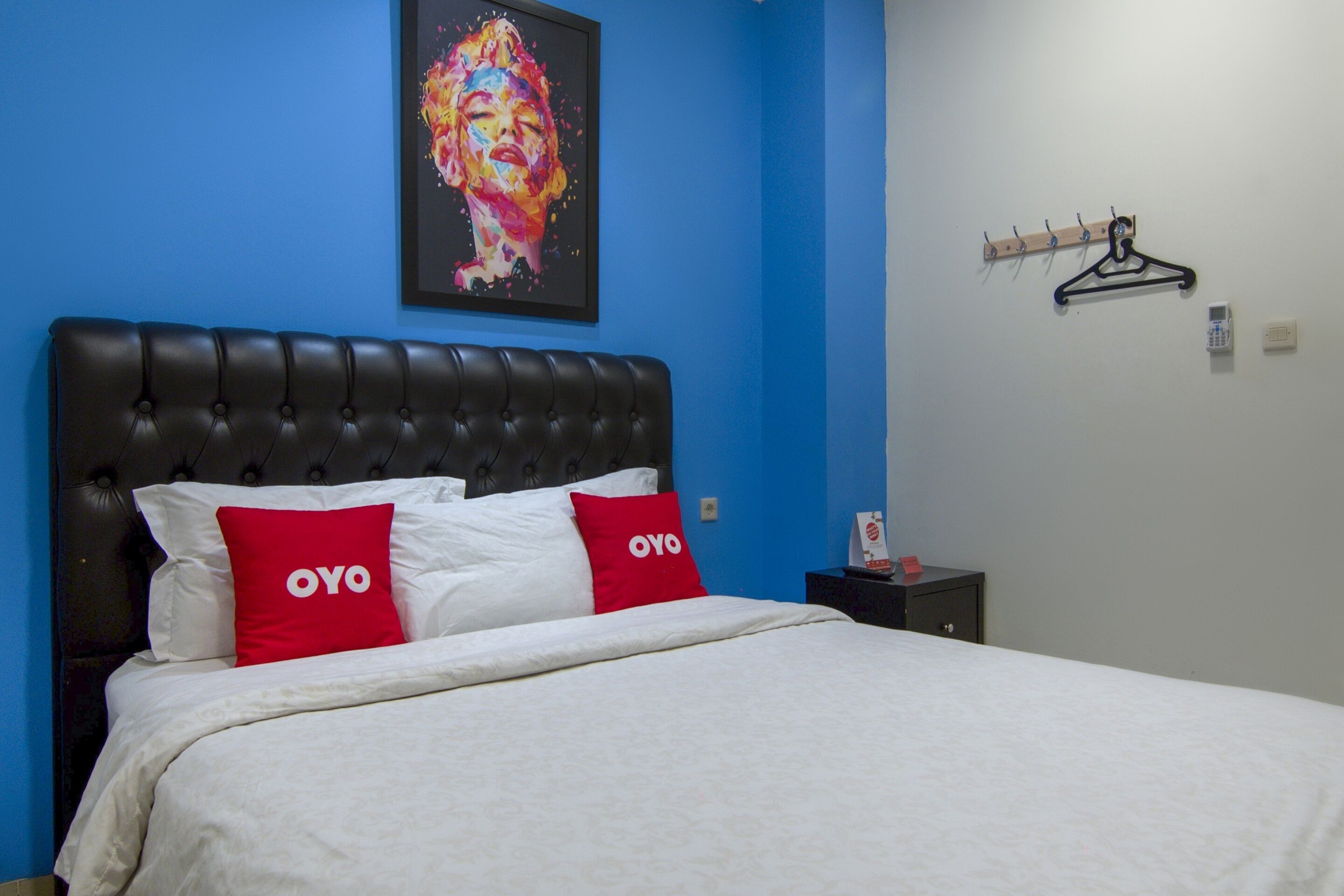 A bed with a black headboard, white bedding, and two red pillows with the text "OYO".