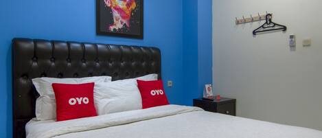 A bed with a black headboard, white bedding, and two red pillows with the text "OYO".